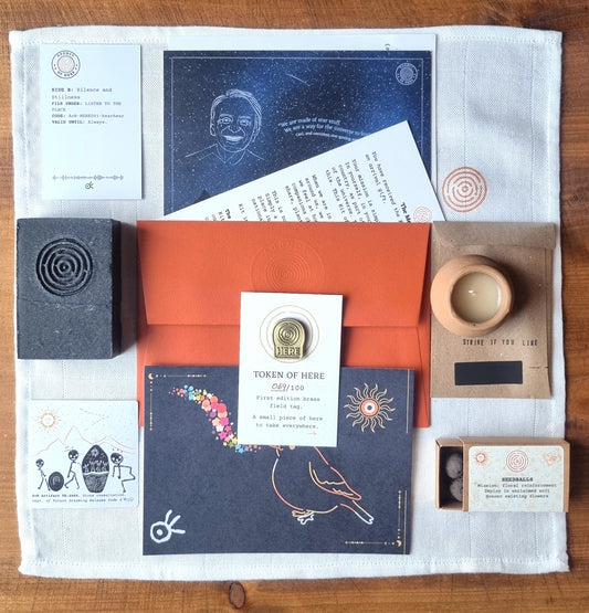 Flatlay showing all objects included in the Kit of Here first edition, including muslin cloth, postcards, candle, soap, seedballs, sticker, matches, QR code, and brass token.
