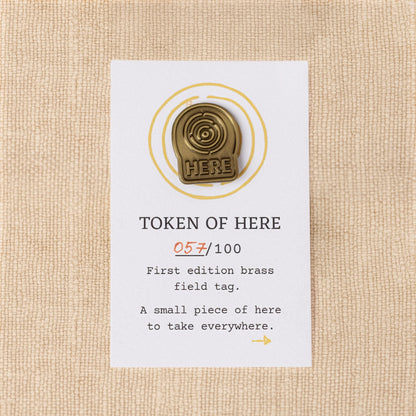 First-edition brass field tag from the Kit of Here with numbered backing card, made to carry as a daily reminder of place.