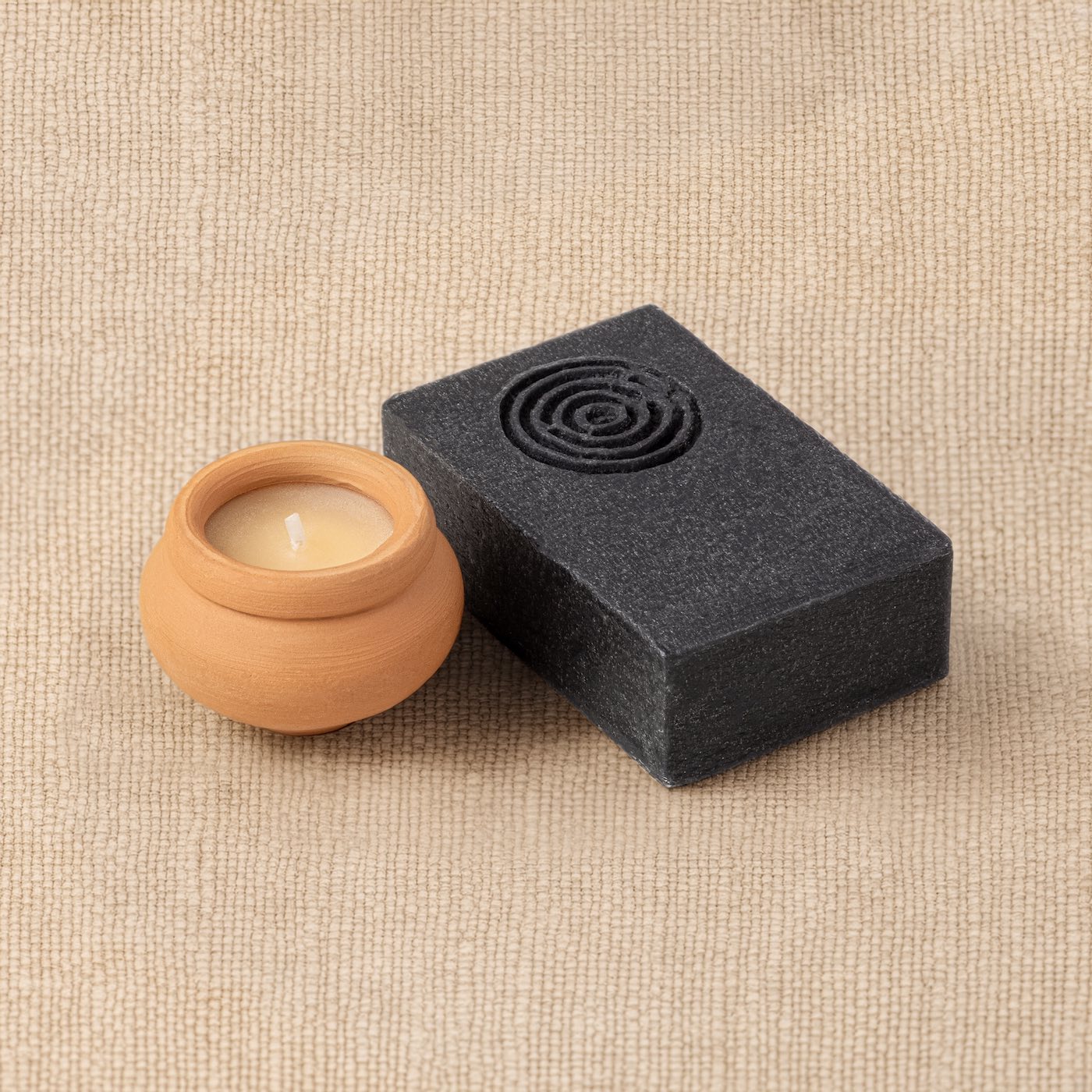 Terracotta candle and lime and rosemary soap from the Kit of Here arranged together on a linen surface.