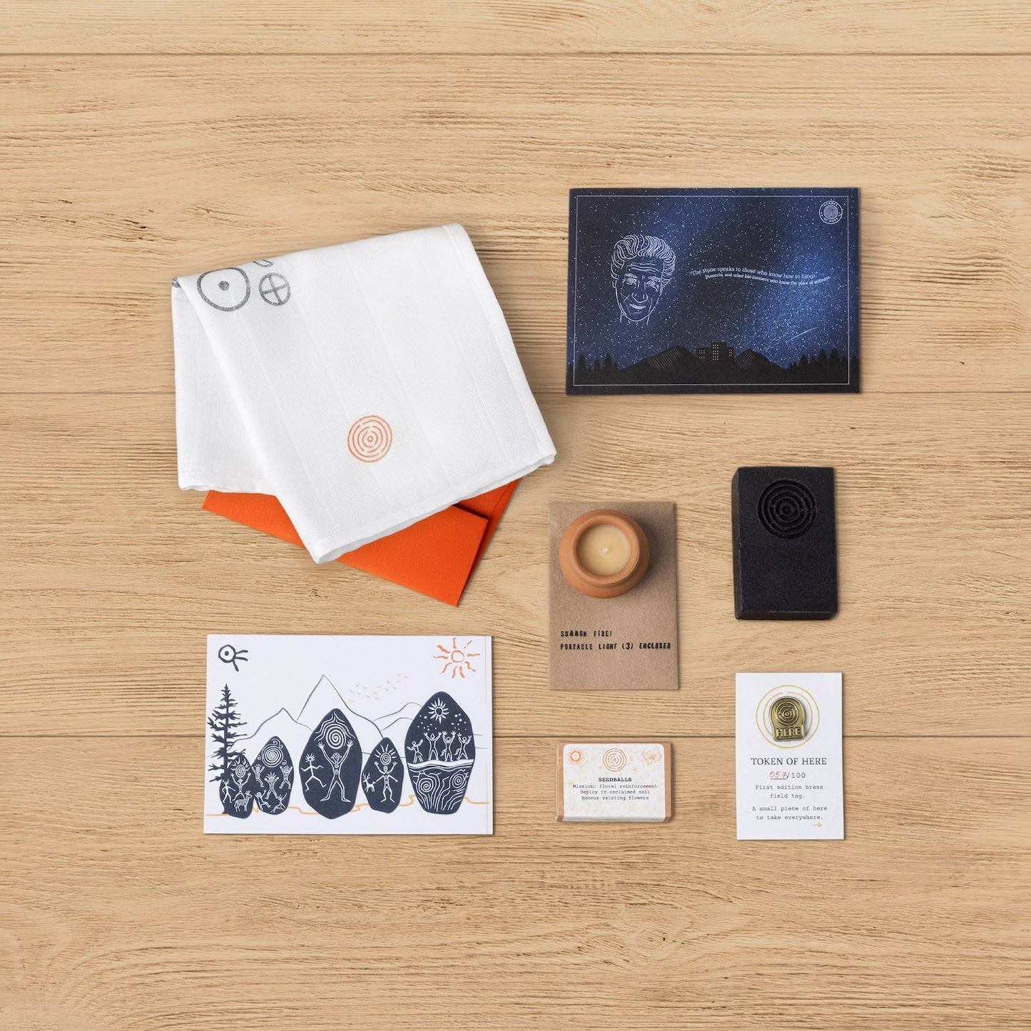 Flatlay showing all objects included in the Kit of Here first edition, including muslin cloth, postcards, candle, soap, seedballs, and brass token.