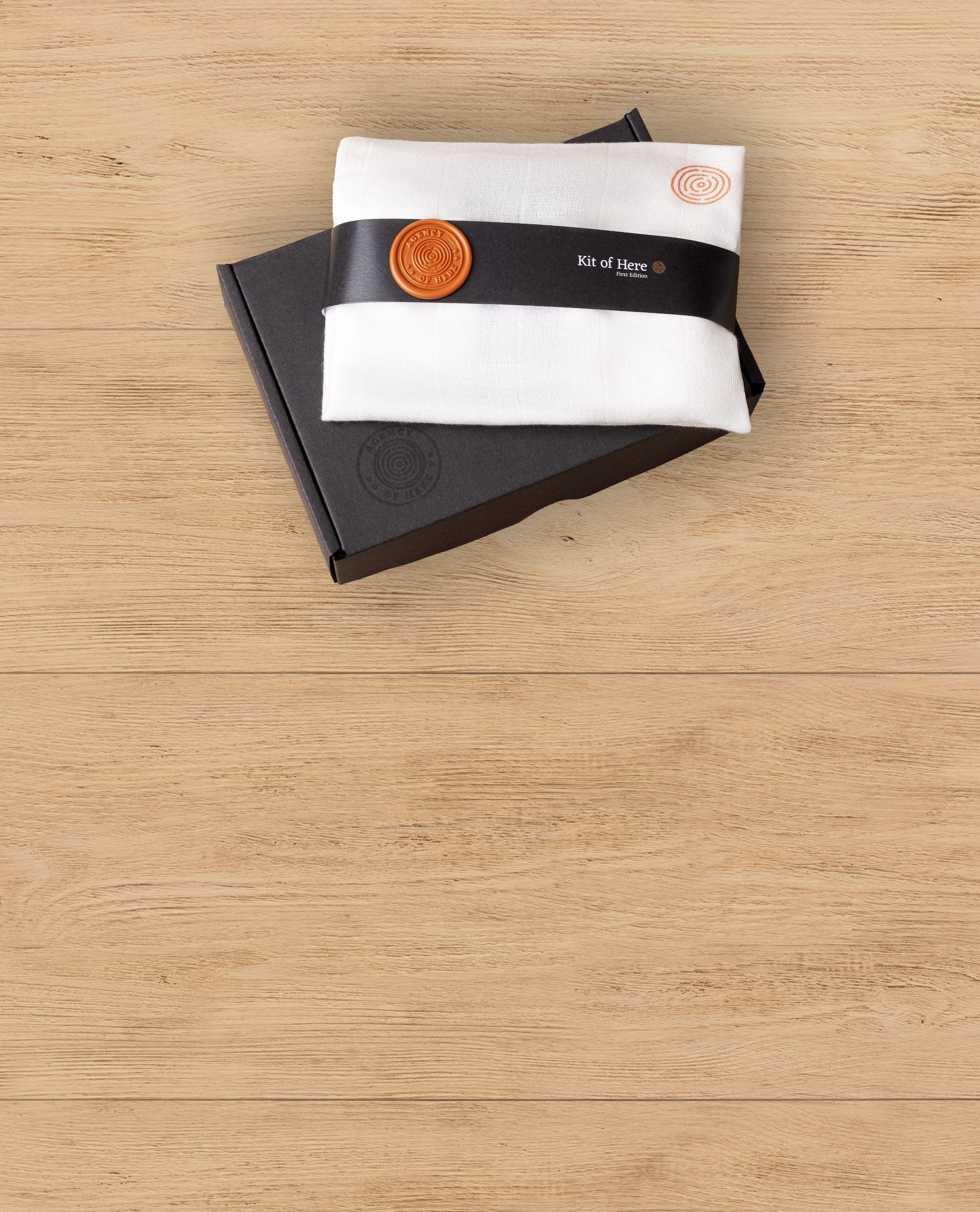 The Kit of Here gift box with a muslin-wrapped package and wax seal resting on top.