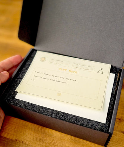 Gift note on top of white reveal card and charcoal felt in box of the Kit of Here