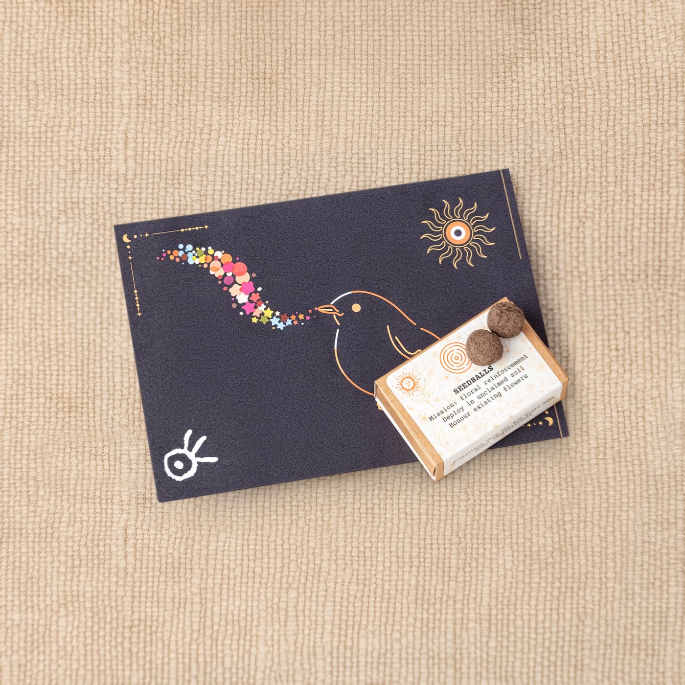 Product photo of wildflower seedballs placed on top of illustrated postcards from the Kit of Here.